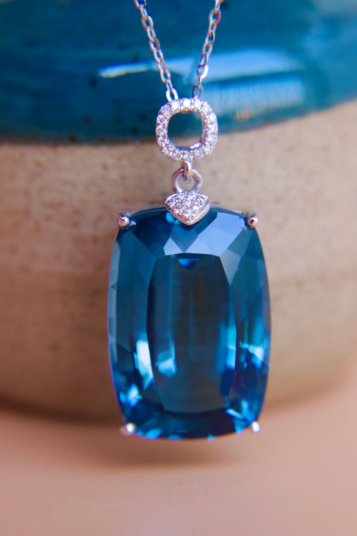 18K Gold Topaz and Diamond Pendant: This pendant is exquisitely set in 18K gold, showcasing the unique allure of the London Blue diamond. The center stone boasts a captivating color and flawless clarity; paired with a substantial gold s