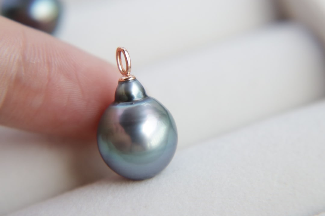 18K Gold Tahitian Sea Pearl Pendant: This pendant is meticulously crafted in 18K gold, featuring a 12mm Tahitian sea pearl with flawless peacock green luster. The pearl's strong shine and subtle growth lines complement each other, showca