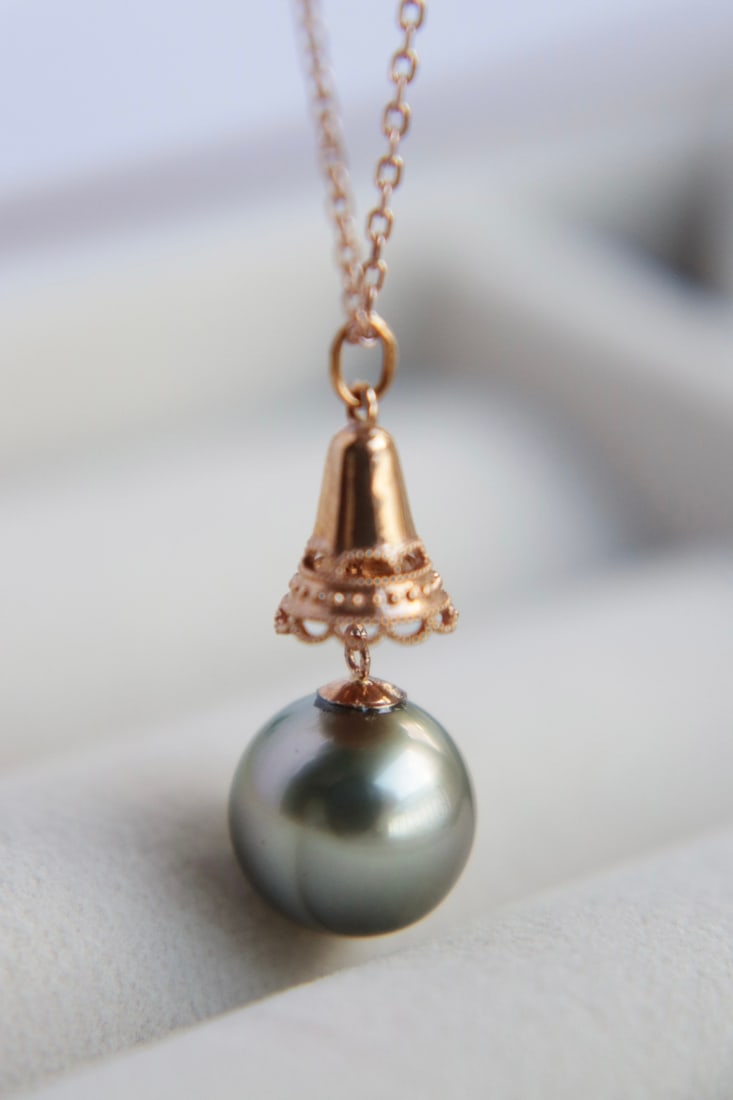18K Gold Tahitian Pearl Pendant: This pendant is meticulously crafted in 18K gold, featuring a Tahitian pearl that showcases its natural luster and flawless quality. The pearl measures 11mm in diameter, exhibiting a captivating stron