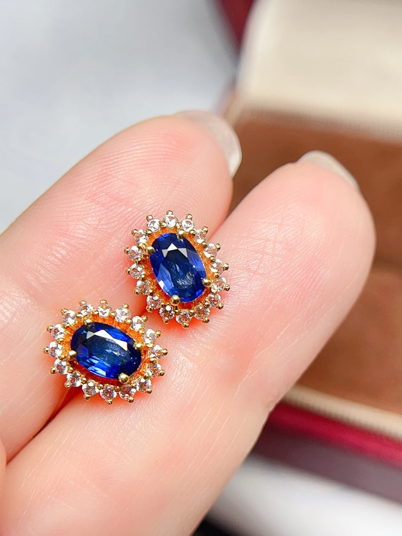 18K Gold Royal Blue Sapphire Earrings: These earrings are crafted in 18K gold, featuring royal blue sapphires that embody the classic Princess Diana style. The main stone is richly colored and transparent, complemented by 32 white sapphire