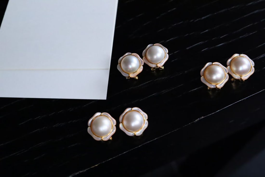 Sterling Silver Seawater Mabe Earrings: These earrings feature white mother-of-pearl, resembling a dainty daisy, exuding a gentle glow. The 12mm seawater Mabe, with its golden edges, adds an elegant touch. The design is understated yet exqu