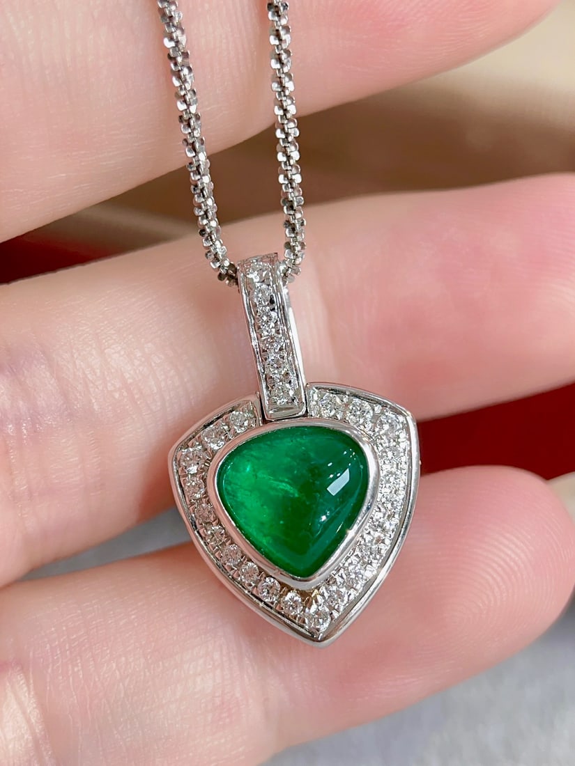 18K Gold Emerald Pendant: This pendant is crafted in 18K gold, featuring an emerald with a lustrous and translucent crystal. The emerald's color is deep and rich, reminiscent of Muzo. The cabochon design enhances its natural b