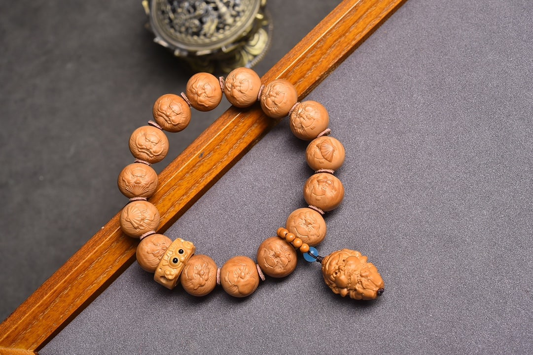 Natural Original Seed Monkey Head Walnut Bracelet: This bracelet is carved from natural original seed monkey head walnuts, with each piece carefully selected to ensure no impurities or cracks. It is paired with an olive core Yellow God of Wealth penda