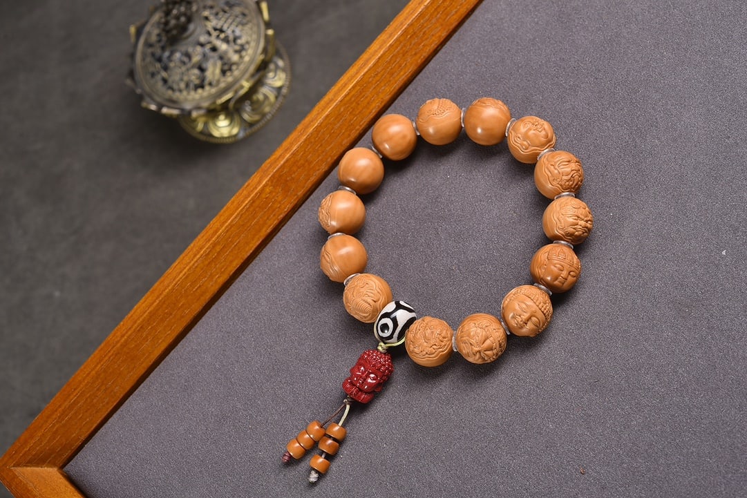Natural Monkey Head Walnut Bracelet: This bracelet is crafted from natural monkey head walnuts, each carefully selected to ensure no impurities or cracks. Paired with three-eyed agate dzi beads and a purple-gold cinnabar Buddha, it showc