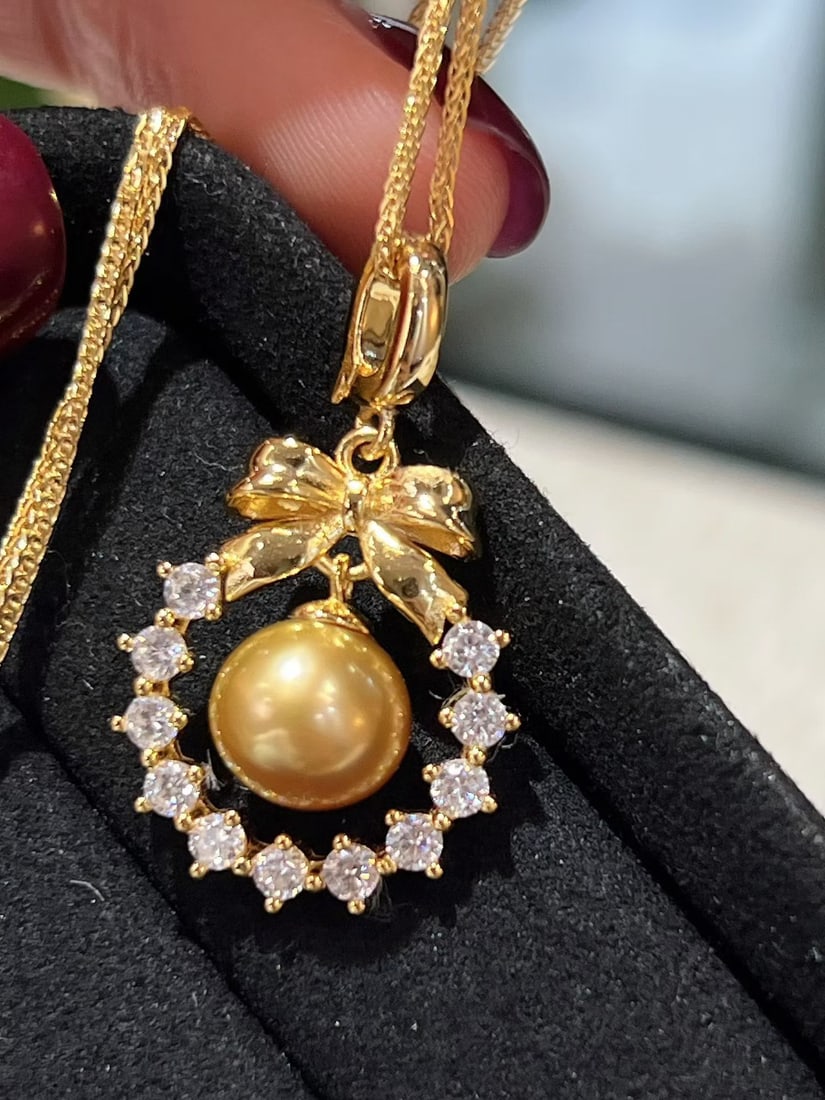 Golden Sea Pearl Pendant: This pendant features a golden sea pearl with a vibrant luster. The classic silver clasp design suits various styles. The pearl is nearly round and virtually flawless, showcasing its noble quality.pea
