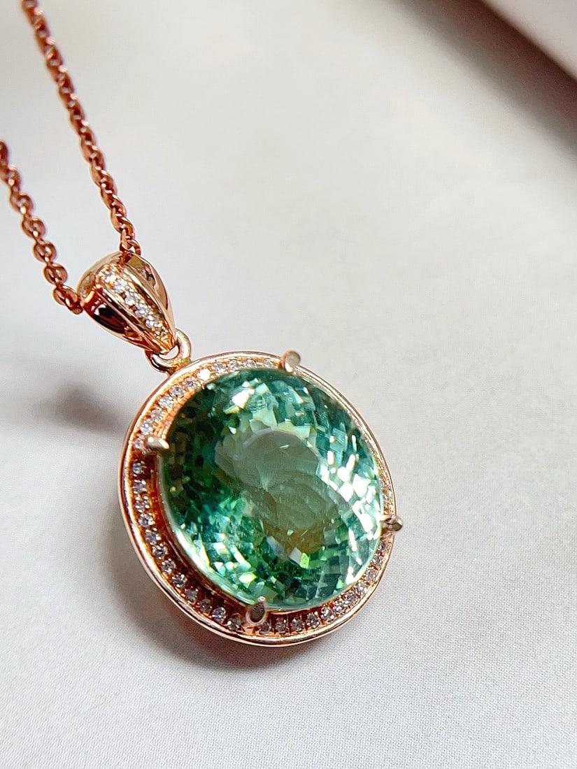 18K Gold Blue-Green Tourmaline Pendant: This pendant is crafted from 18K gold, featuring a blue-green tourmaline with a glass-like luster. The exquisite cut enhances its brilliance under light, captivating the beholder. The addition of diam