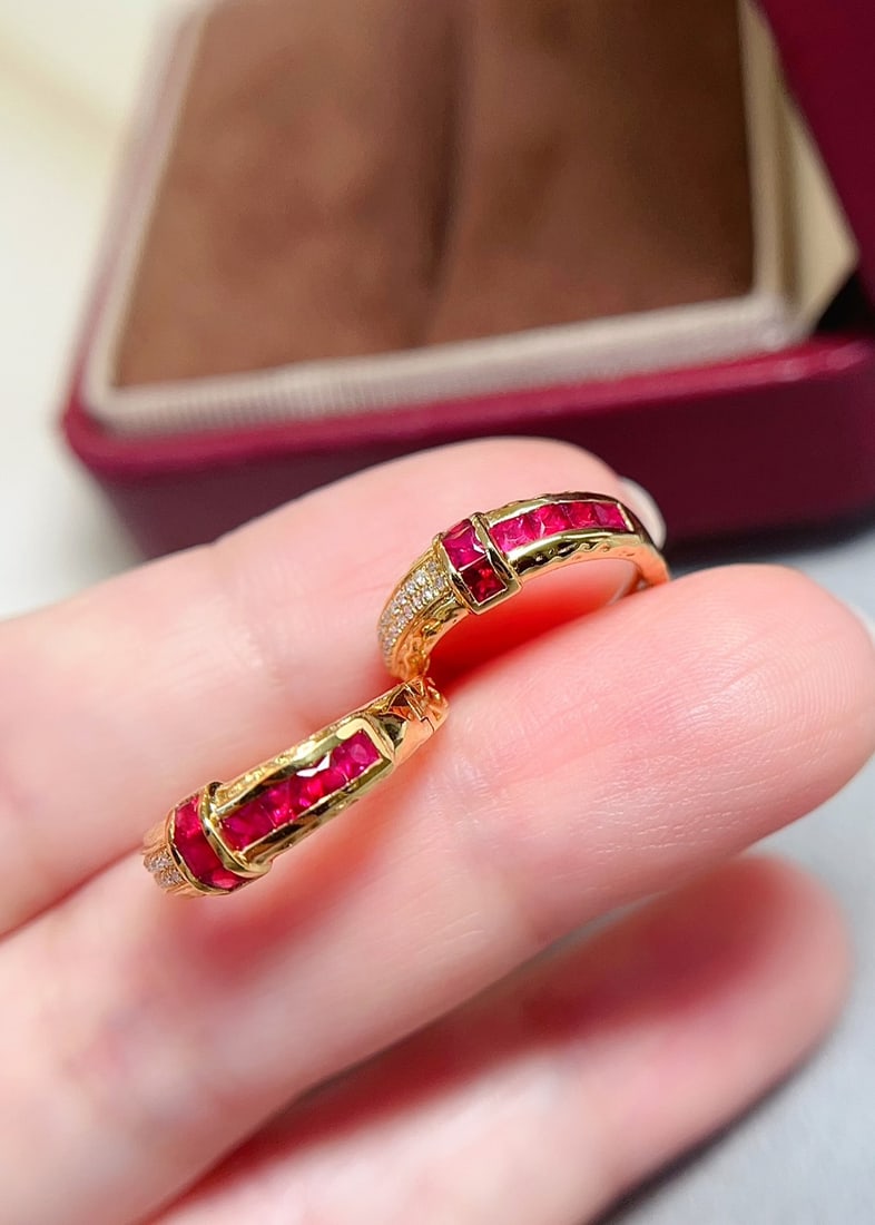 18K Gold Natural Pigeon Blood Red Ruby Earrings: These earrings are meticulously crafted in 18K gold, showcasing the captivating pigeon blood red hue of the ruby. The bezel-free setting highlights the brand's design flair. Adorned with 40 diamonds, 