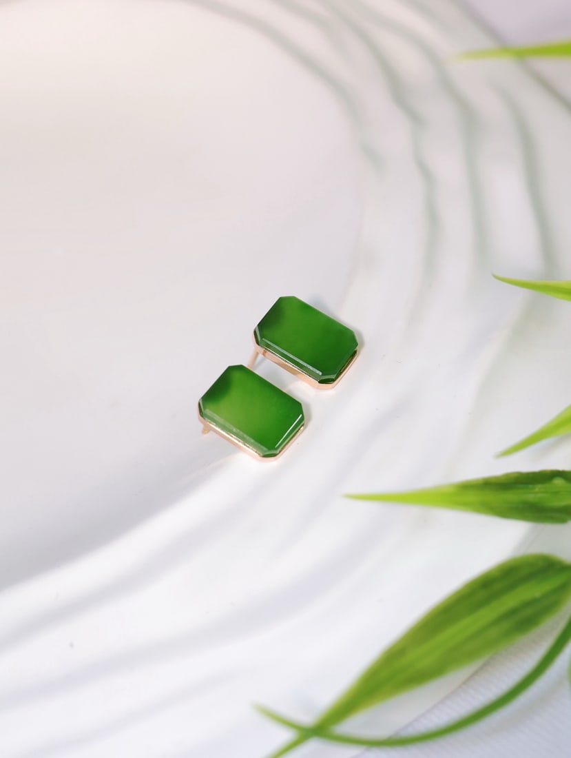 18K Gold Hetian Jasper Earrings: These earrings are meticulously set in 18K rose gold, showcasing the fine and lustrous texture of Hetian jasper. The jade surface exudes a charming green luster, with a square design that enhances ele