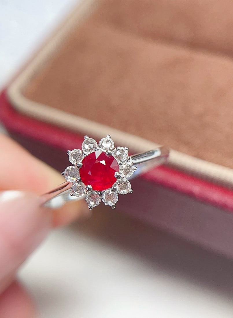 18K Gold Pigeon Blood Red Ruby Ring: This ring is meticulously crafted in 18K gold, featuring a pigeon blood red ruby that radiates a warm glow like a small sun. The ruby's rich and captivating hue is complemented by 10 white sapphires, 
