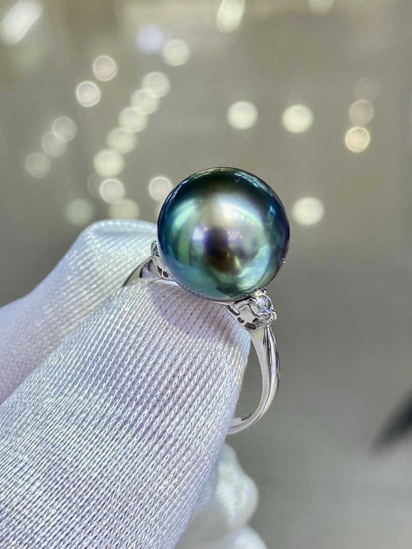Platinum Peacock Green Ring: This ring features a perfect peacock green pearl, showcasing an unparalleled elegance with its top-grade color. The pearl is perfectly round with slight blemishes, set in pt900 platinum band, exuding