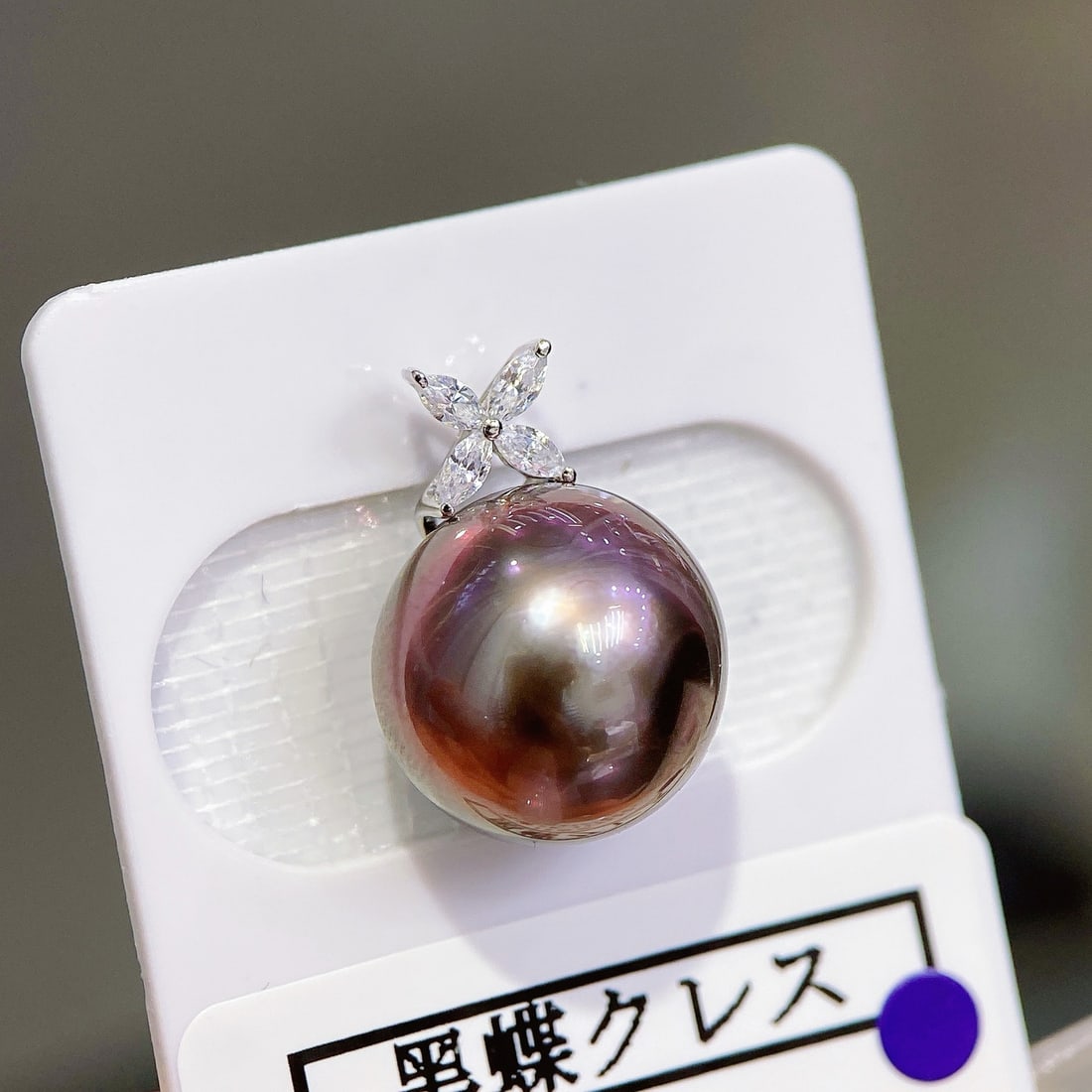 18K Gold Tahitian Pearl Pendant: This pendant features an 18K gold setting with a Tahitian pearl, measuring 12mm in diameter, showcasing an enchanting peacock purple hue. The pearl has very slight blemishes, maintaining an overall cl