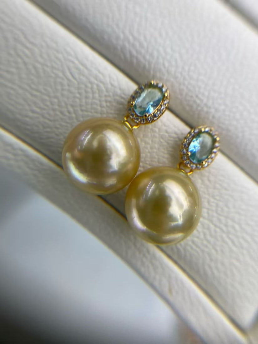 Natural Slightly Flawed South Sea Gold Pearl Earrings: These earrings showcase a gentle hue and versatile design, reflecting a unique taste. Each South Sea gold pearl measures 13-14mm in diameter, with slight flaws and delicate ripples that do not affect 