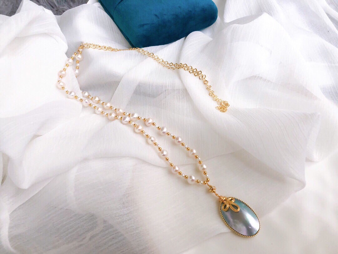 Natural Mabe Pearl Pendant: This sweater Pendant elegantly combines natural Mabe pearls with metal, showcasing a unique sense of sophistication. The silver-blue Mabe pearls complement the woven design, enhancing the overall styl