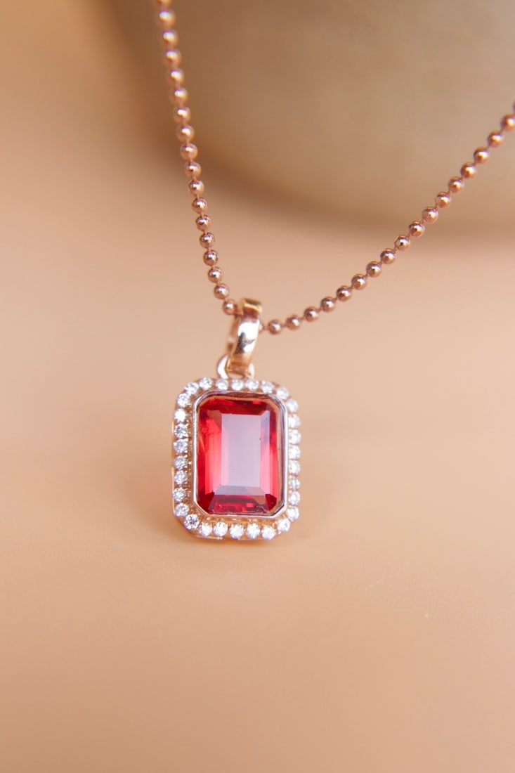 18K Gold Ruby-Color Sunstone Diamond Pendant: This pendant is meticulously crafted in 18K gold, set with a ruby-color sunstone that displays enchanting hues. The thick gold setting, paired with brilliant diamonds, exudes luxury. Perfect for any o