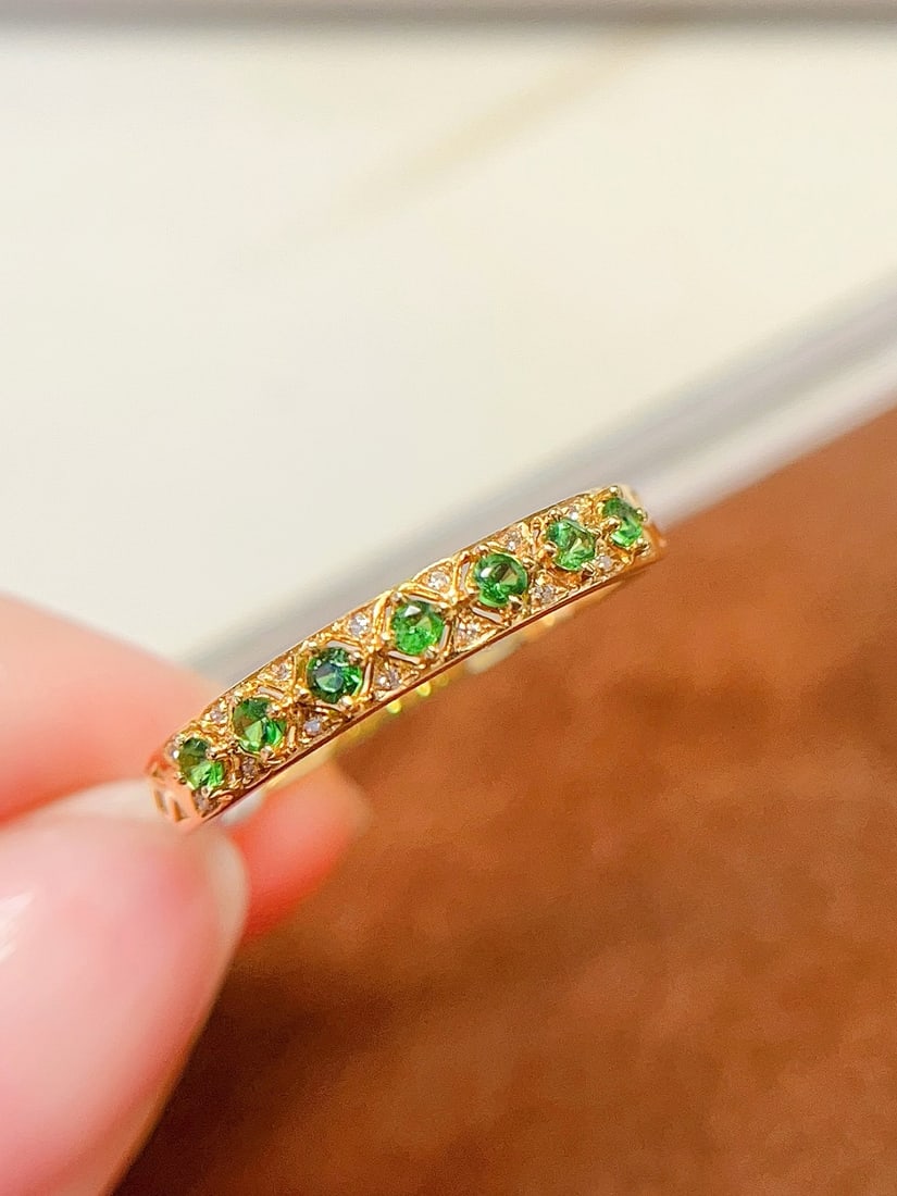 18K Gold Natural Tsavorite Ring: This 18K gold ring is set with a natural tsavorite, showcasing an elegant design. The round band design makes it a classic choice, suitable for various occasions. The brilliance of the main stone comp