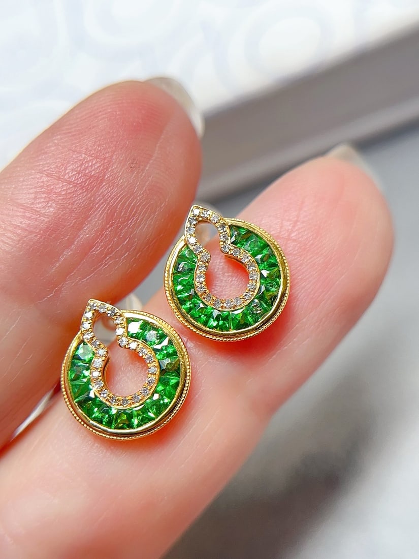 18K Gold Natural Tsavorite Earrings: These earrings are crafted from 18K gold, showcasing a unique vivid green hue. The bezel-free setting with a gourd shape exudes a sense of fashionable luxury. The main stone is approximately 0.7 carat