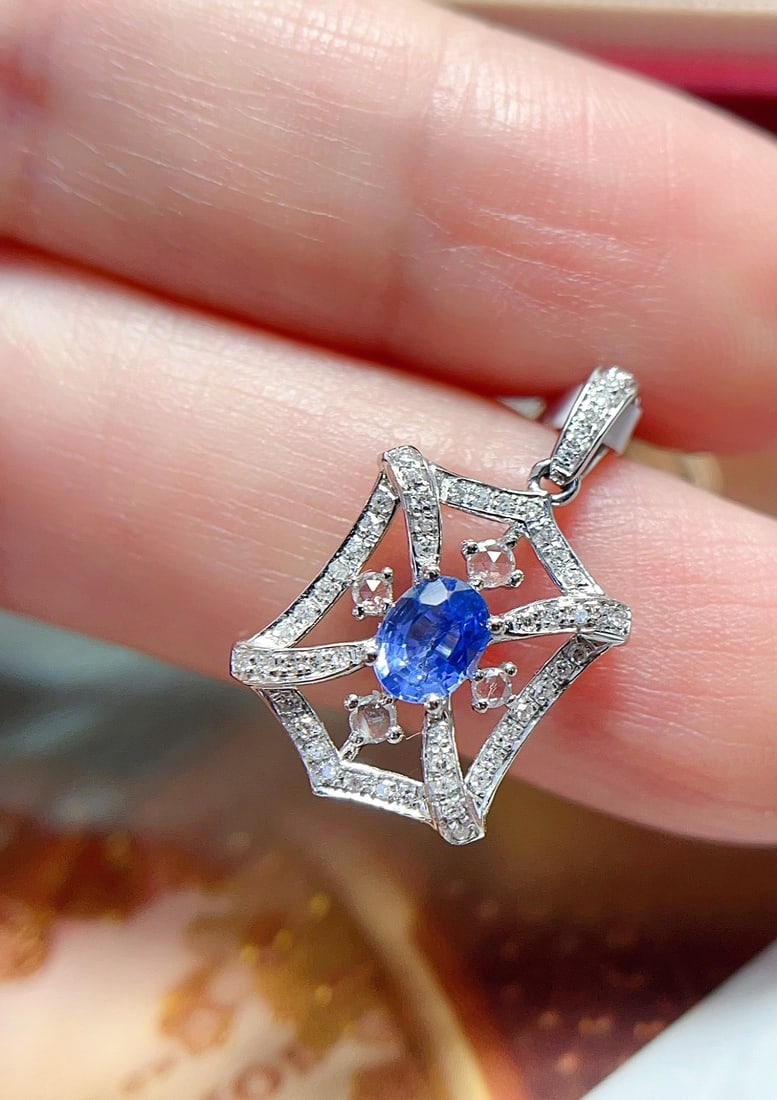 18K Gold Sapphire Pendant: This pendant is meticulously crafted in 18K gold, with a sapphire that shines like a cornflower. The unique design exudes elegance. The main stone is approximately 0.4 carats, complemented by 54 diamo