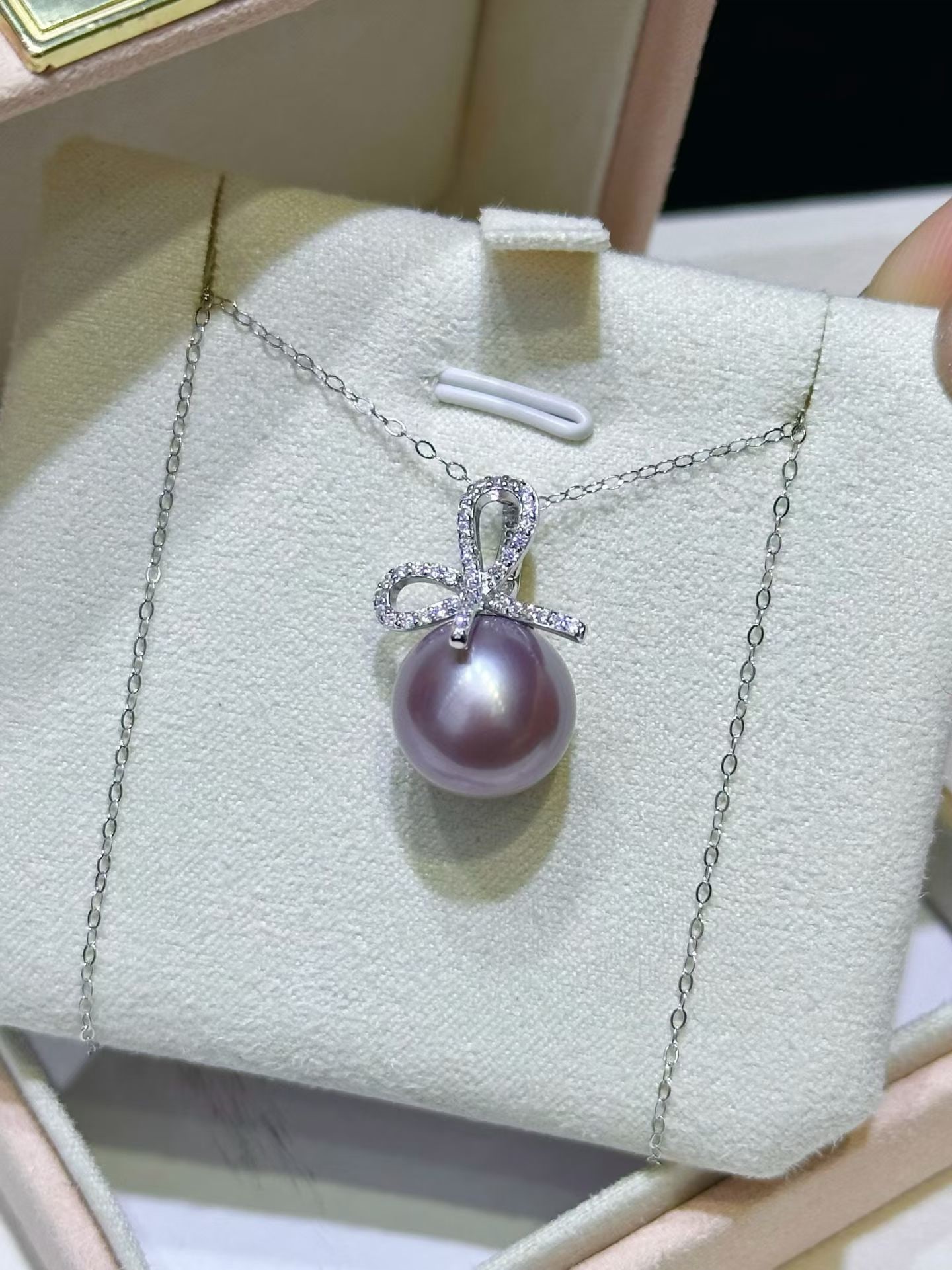 Silver Edison Pearl Pendant: This pendant features an elegant bow design, paired with a 12-13mm round Edison pearl, showcasing the pearl's high luster. The slightly blemished pearl enhances its natural beauty, and the silver univ