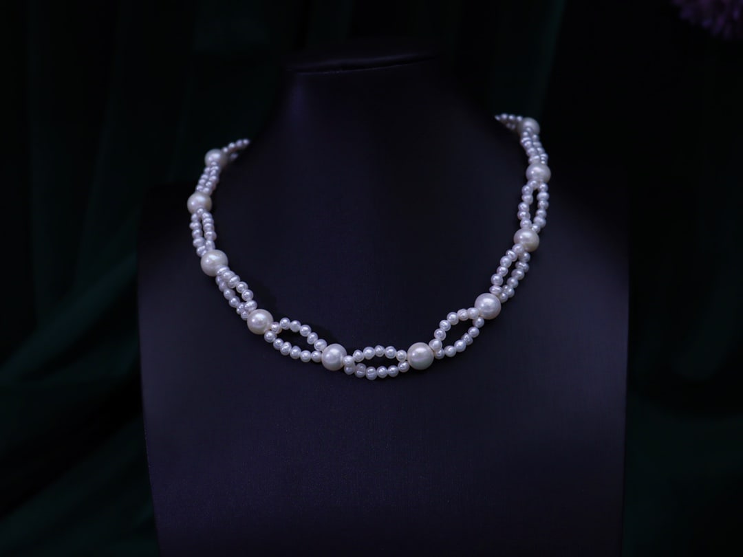 Handcrafted Pearl Necklace: This necklace features pearls of varying sizes, intricately handwoven in a lace-like pattern, complemented by a textured bow clasp. The overall design is elegant, suitable for daily wear. (Length 40 c