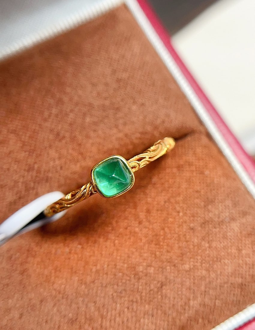 18K Gold Emerald Ring: This ring is crafted in 18K gold with a delicate hollow pattern band. The emerald exhibits a captivating spicy green sugarloaf hue, princess cut, clean with fluorescence. (Main stone approx. 0.4 carat