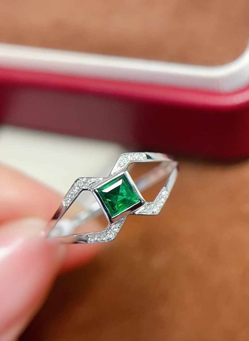 18K Gold Emerald Ring: This ring is crafted in 18K gold, featuring a princess-cut emerald in a simple yet exquisite design. The main stone is approximately 0.35 carats, complemented by 20 diamonds, creating a delicate and e