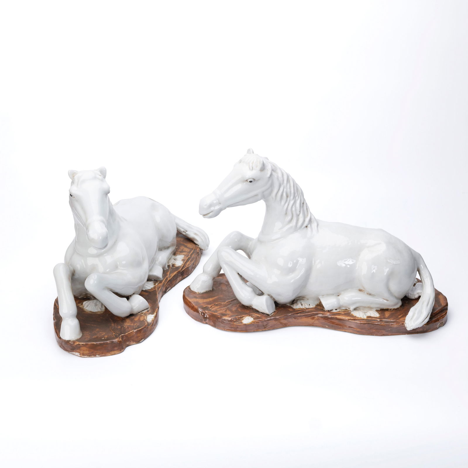 Two White Porcelain Horse Figurines on Brown Cera: Two White Porcelain Horse Figurines on Brown Ceramic Bases H: 9 1/2 inches W: 15 inches D: 6 1/2 inches