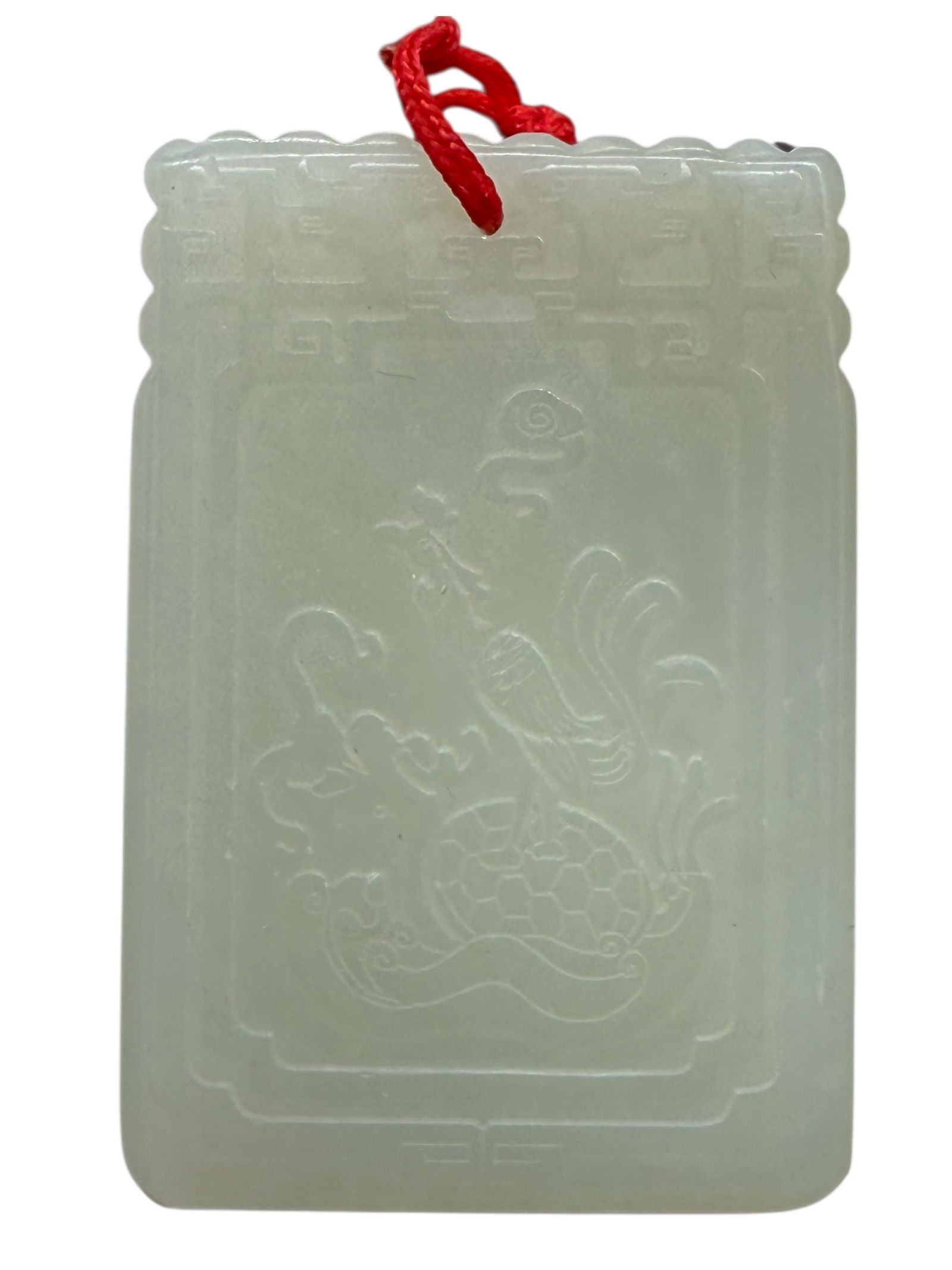 A Chinese Celadon Jade ‘Dragon’ Plaque: The rectangular plaque carved in low relief with a frontal dragon amid clouds within a geometric border, the reverse incised with a poetic inscription. H: 2 inches