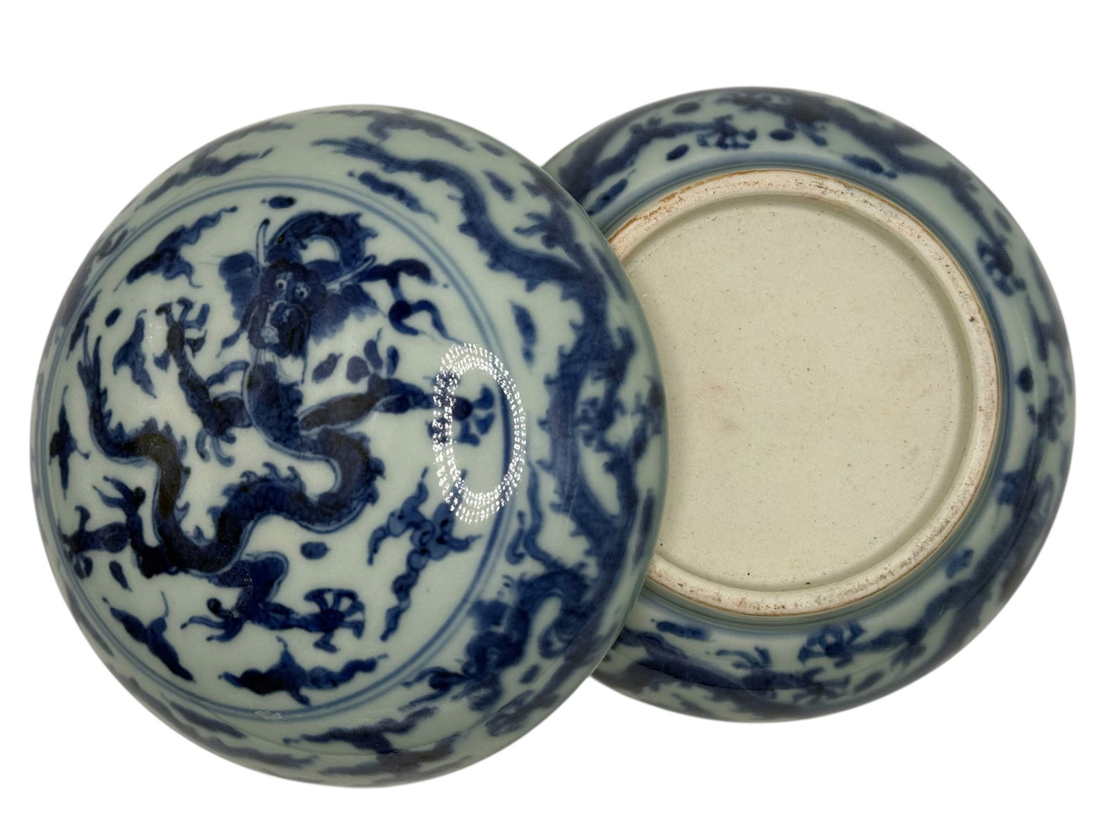 A Chinese Blue and White Dragon Box with Lid: Painted in underglaze blue with a dragon in pursuit of a flaming pearl amid clouds, the base unglazed. H: 3 1/4 inches W: 5 inches
