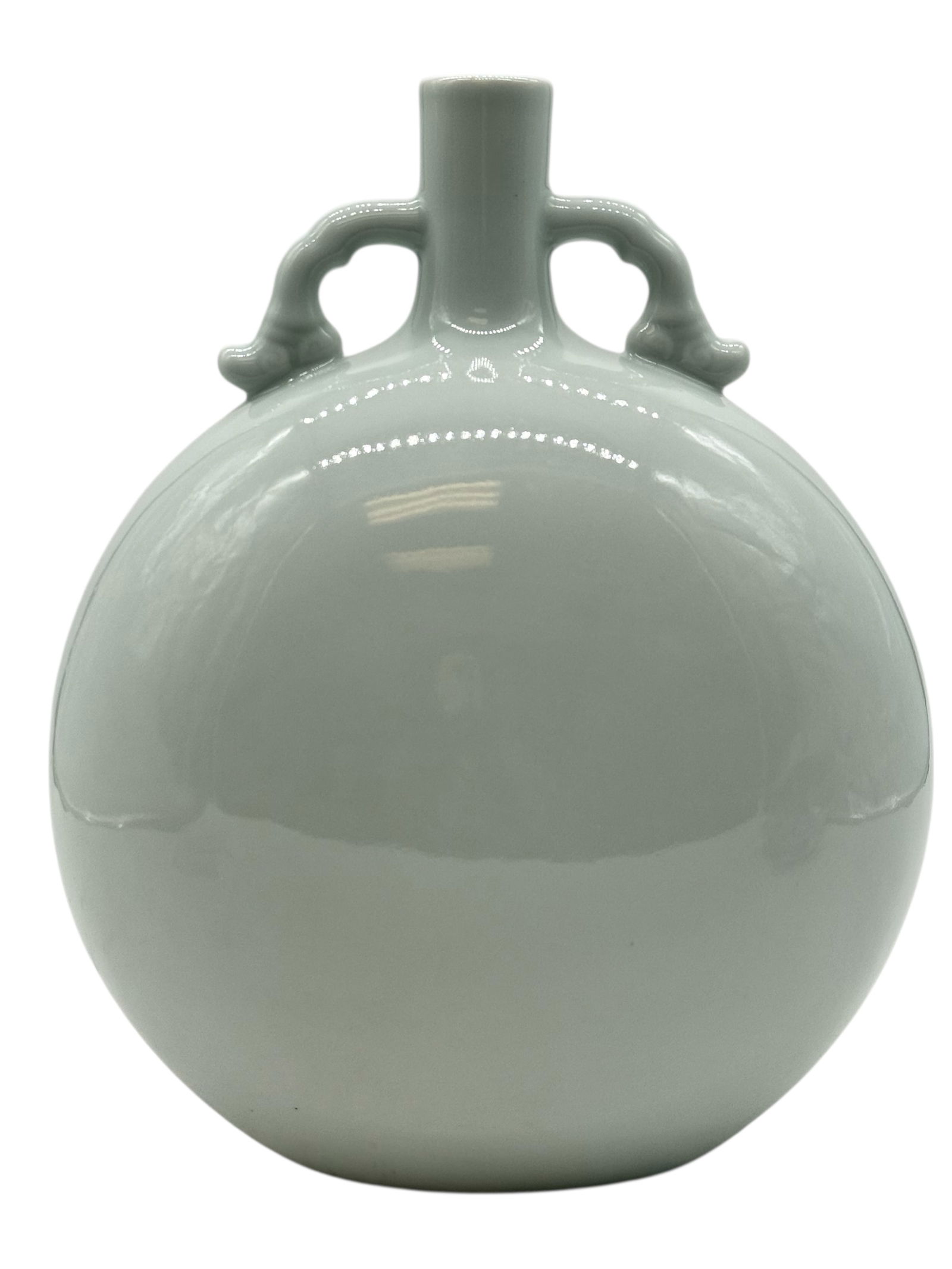 A Chinese White Celadon-Glazed Moon Flask: The flattened globular body rising to a short cylindrical neck, flanked by a pair of loop handles at the shoulder, covered overall with a pale celadon glaze. H: 11 1/2 inchesW: 10 inches