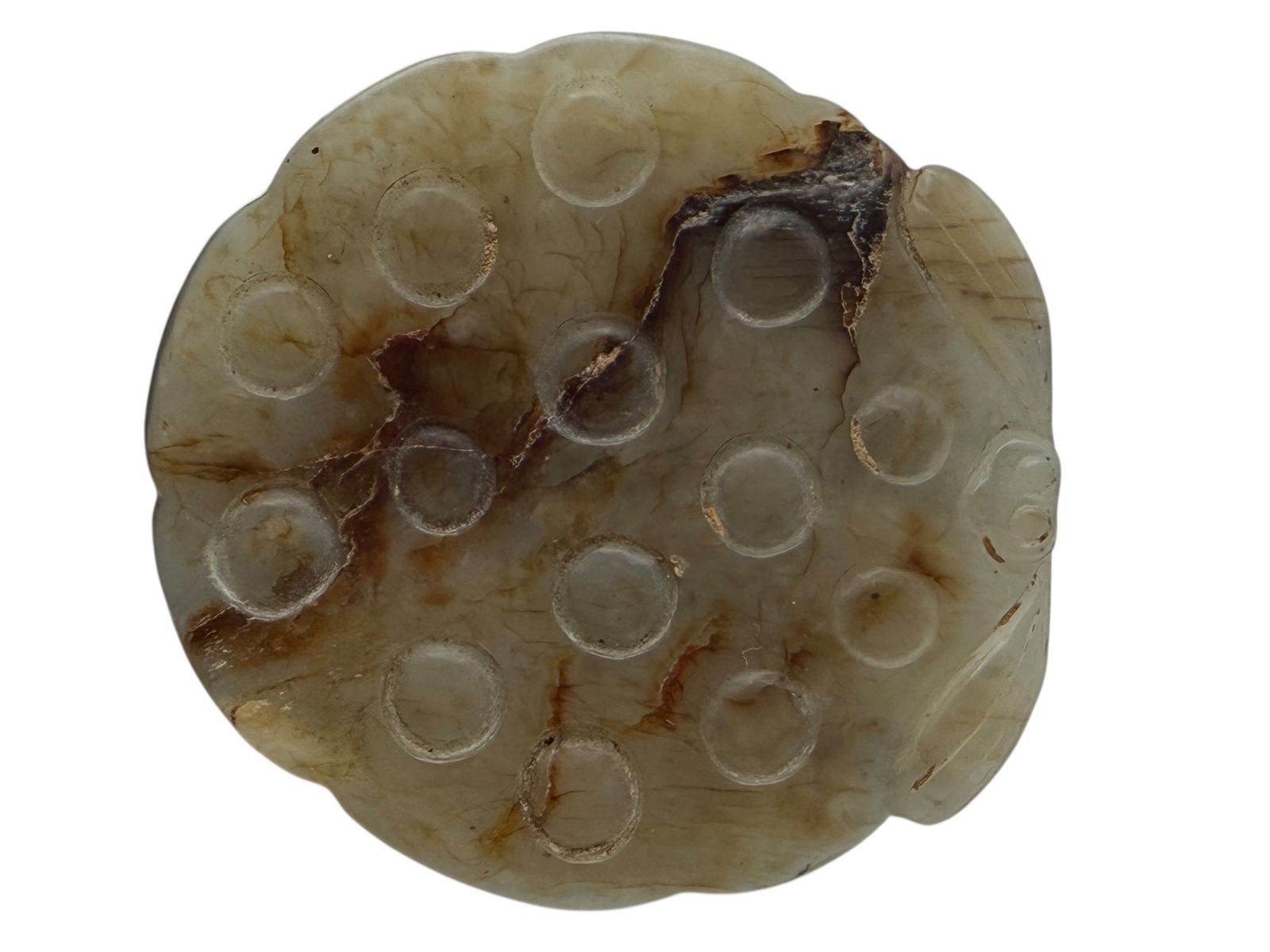 A Chinese Carved Jade Lotus Root: A Chinese Carved Jade Lotus RootCarved as a lotus root section with multiple round openings, showing natural russet inclusions and veining. H: 1 1/2 inches W: 2 inches