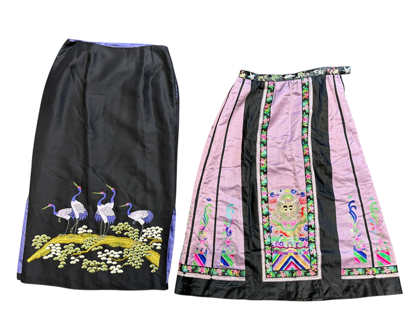 Two Chinese Embroidered Skirts: Two Chinese Embroidered SkirtsOne black silk skirt with crane embroidery; one lavender and black skirt with floral and mask motifs. H: 30 inches W:13 inches
