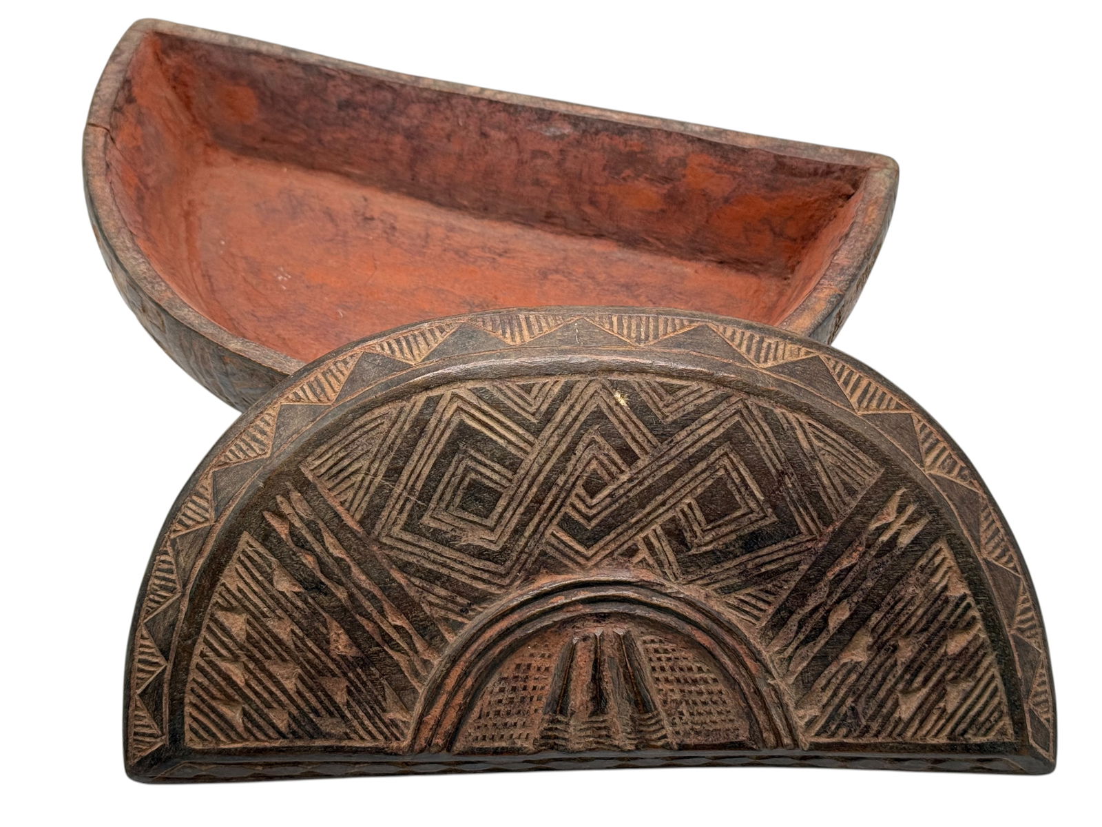 An African Carved Wooden Box with Geometric Decora: An African Carved Wooden Box with Geometric DecoraHalf-moon form with finely incised geometric bands and a reddish interior. H: 2 1/2 inches W: 8 1/4 inches D: 4 inches