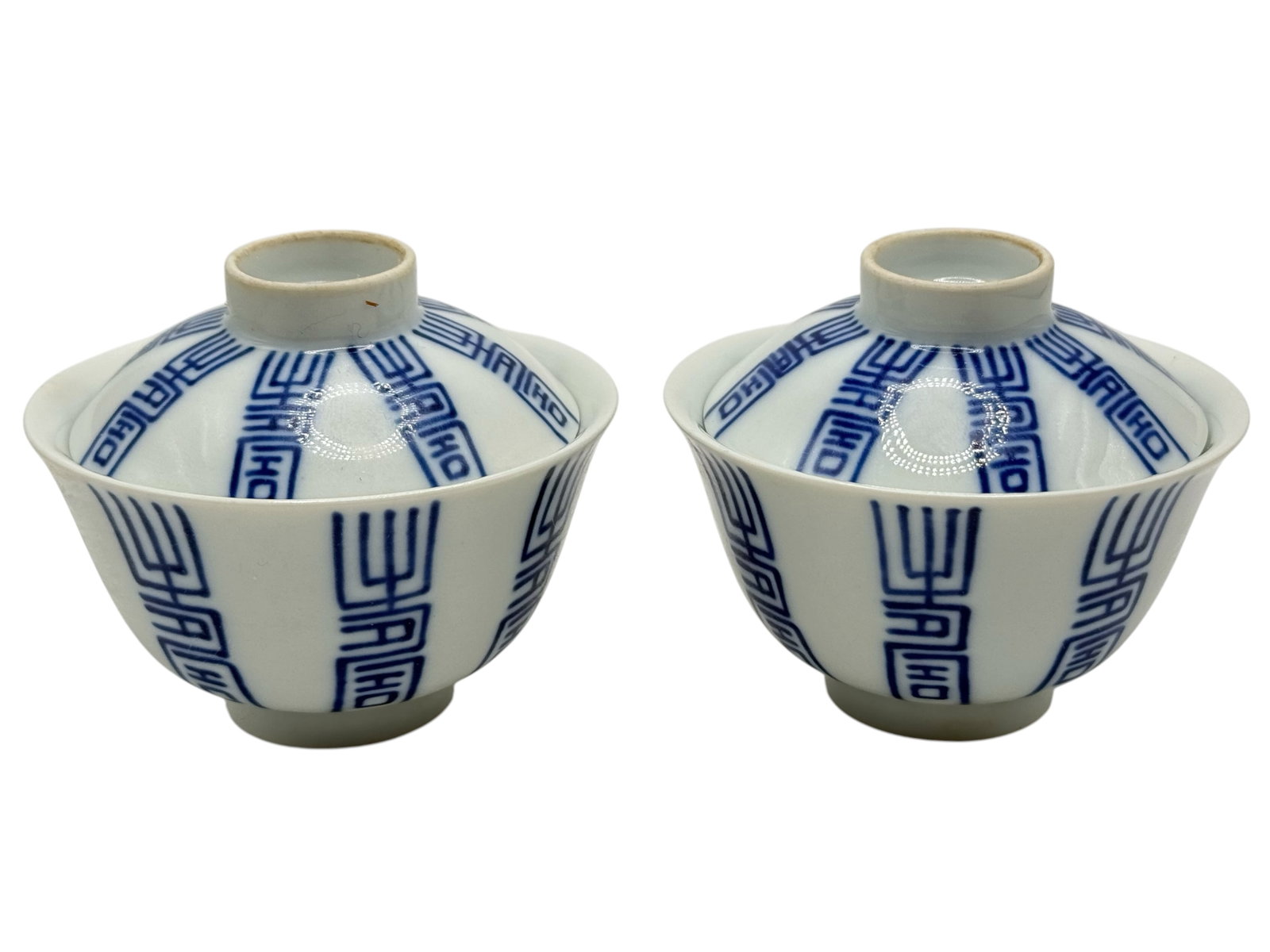 A Pair of Chinese Blue and White Covered Tea Bowls: Decorated with stylized longevity-character motifs throughout. H: 2 1/2 inches W: 3 inches
