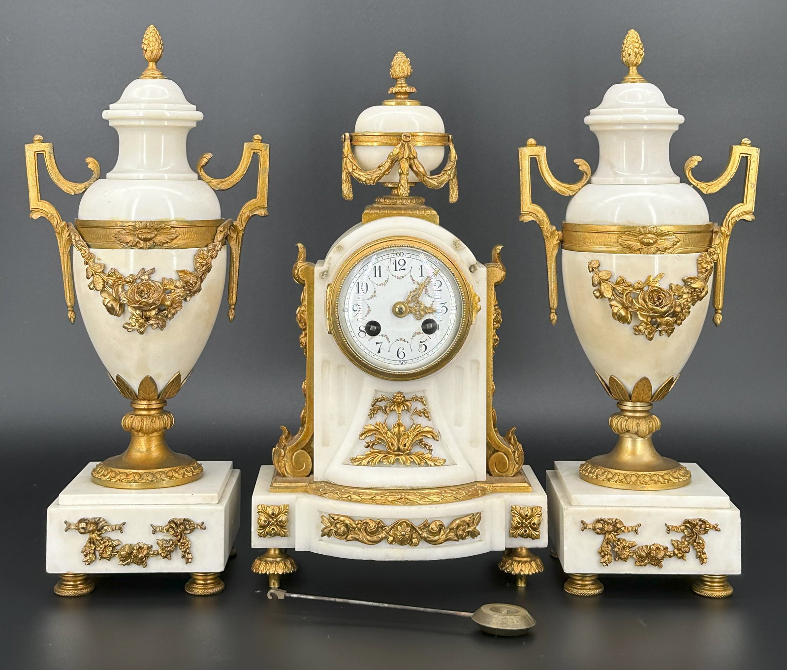 A French Marble and Gilt Bronze Mantel Clock Garni: Comprising a mantel clock and pair of urn-form side pieces, each with gilt bronze floral mounts. Clock : H: 13 inches ; Urn: H:13 1/2 inches