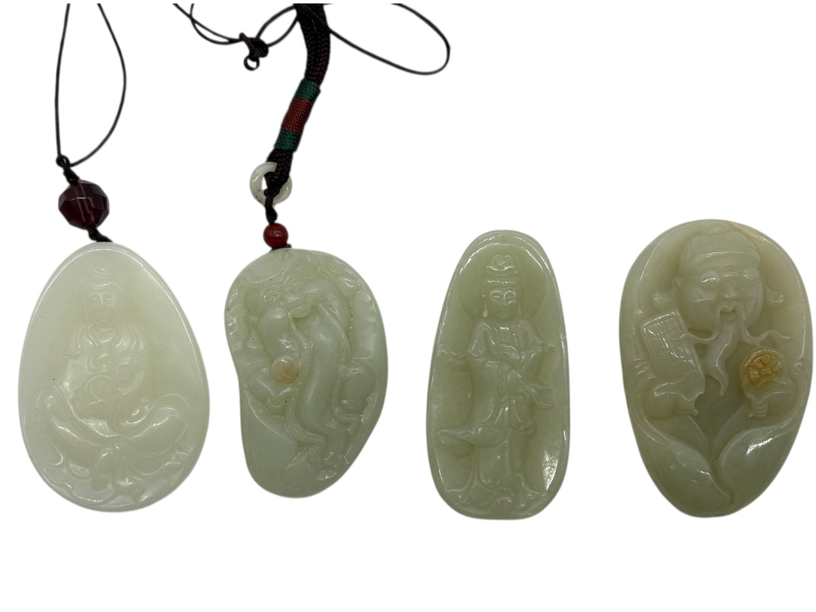A Group of Four Chinese Celadon Jade Carved Pendan: Comprising four celadon jade pendants, each carved in relief with figural subjects including Buddhist and Daoist deities, one depicting Guanyin, one a scholar figure, and others with mythological