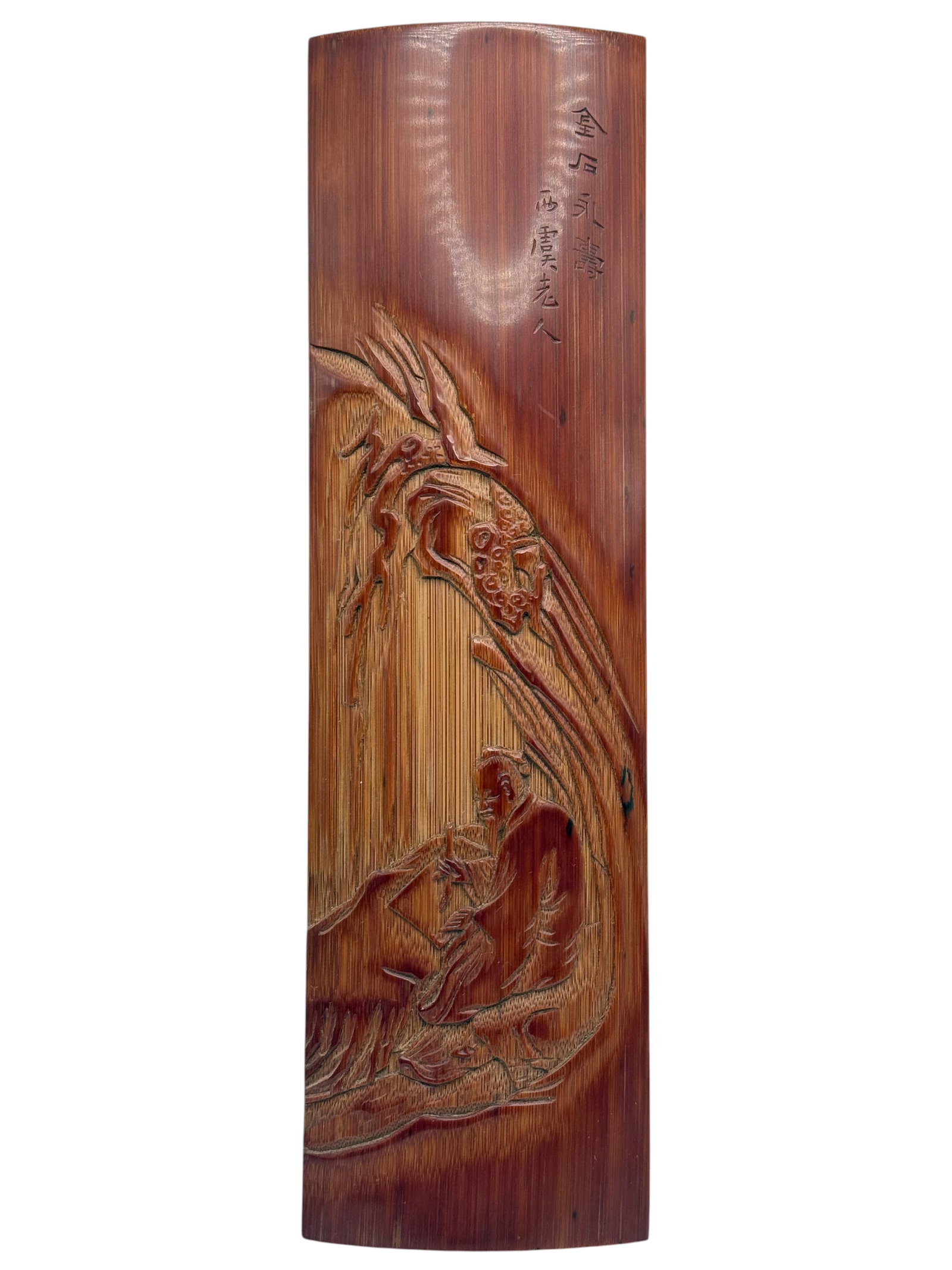 A Chinese Carved Bamboo Paperweight: Rectangular with gently curved profile, carved in relief with a scholar seated beneath bamboo, the upper section inscribed with a poetic inscription; the reverse plain. H: 10 3/4 inchesW: 3 inches