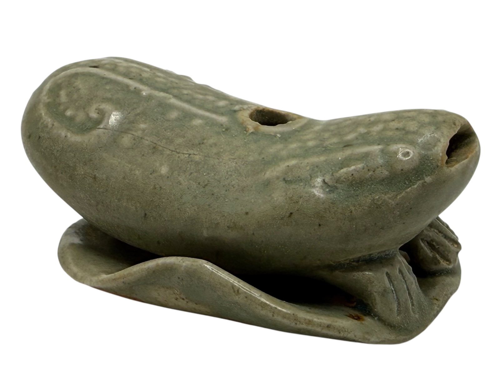 A Chinese Celadon Glazed Pottery Water Dropper: Modelled as a recumbent fish with pierced openings, covered in a celadon glaze.H: 1 1/2 inches W: 4 1/2 inches