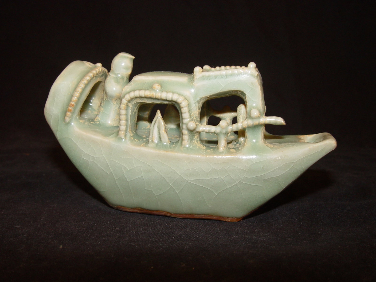 A Chinese Celadon-Glazed Boat-Form Water Dropper: Modeled in the form of a boat with an openwork pavilion, covered in a celadon crackle glaze. 2 1/2" * 5"