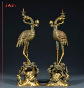 A pair of candlesticks in front of the gilded Buddha