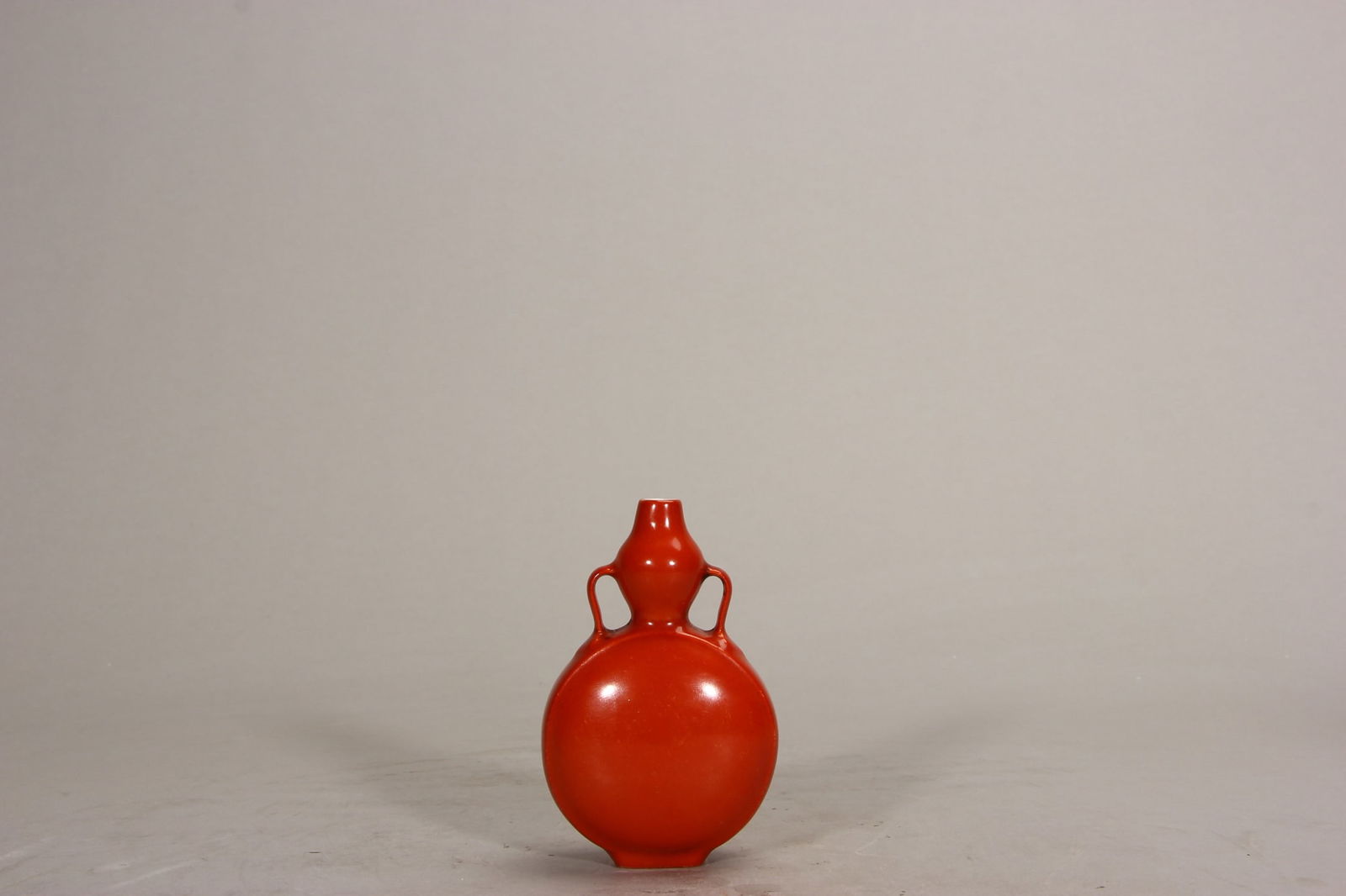 A moon flask with a red glaze and a ribbon handle, Qing Dynasty, Qianlong period: The body of the vase is made of porcelain clay, and its surface is coated with fuchsite glaze. Fuchsite is a low-temperature red glaze with ferric oxide as the main coloring agent. During the process