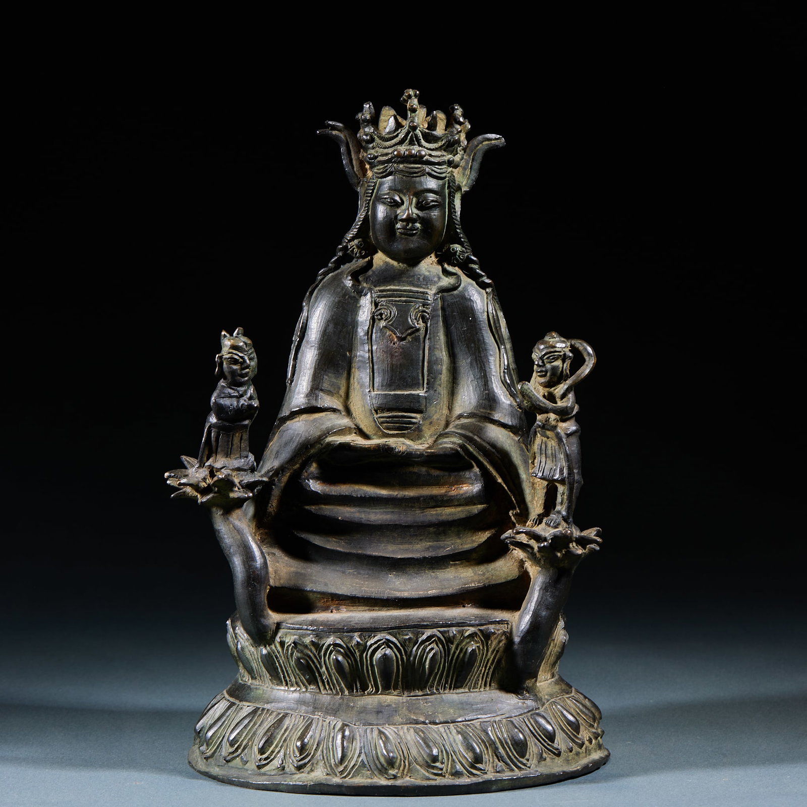 Bronze Boy Attendant Guanyin Seated Statue: Bronze Boy Attendant Guanyin Seated Statue: Cast bronze seated Guanyin flanked by standing boy attendants, benevolent facial features and flowing robe lines. Specifications: height 25cm, length 15cm, 