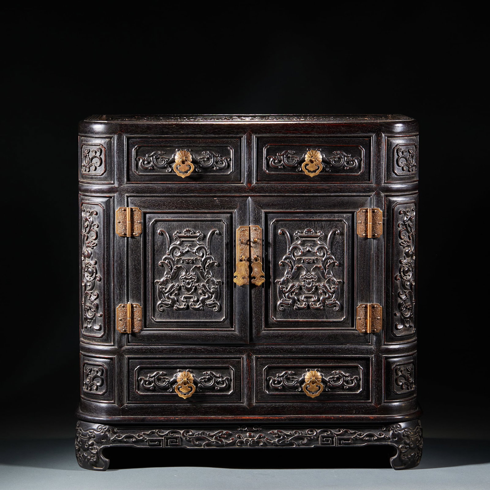 Red Sandalwood Study Cabinet: Red Sandalwood Scholar’s Studio Cabinet: Made of whole red sandalwood log, body fully carved with dragon and interlocking floral patterns, matched with standard copper ornaments and dignified vessel
