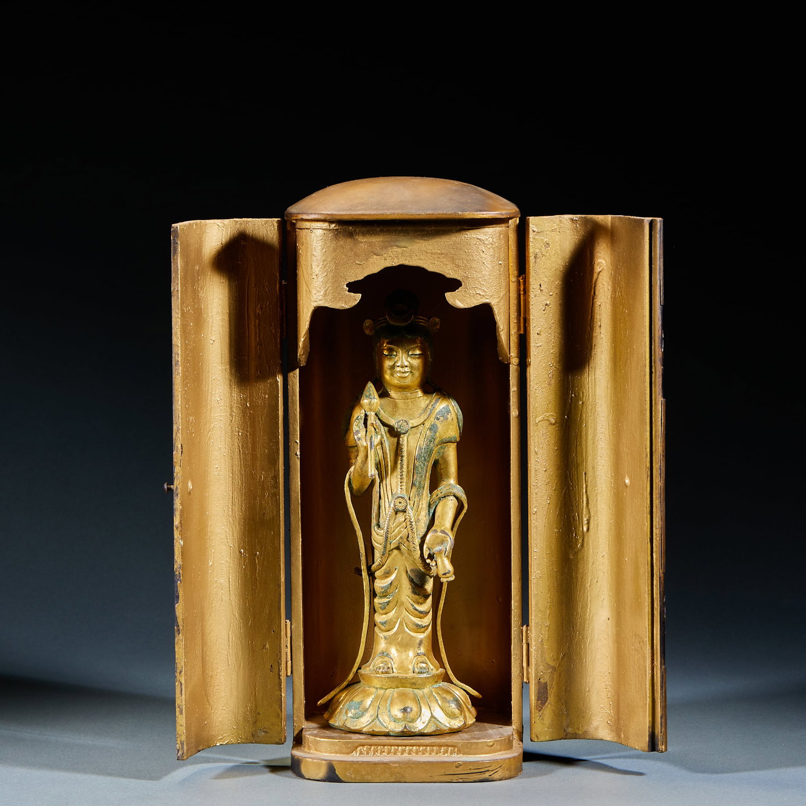 Gilt Bronze Standing Guanyin Holding Lotus, With Wooden Niche: Gilt Bronze Lotus-Holding Guanyin Standing Statue (With Wooden Niche): Gilt bronze with dignified facial features, flowing robe lines and sacred lotus-attiring posture. Preserved complete with origina