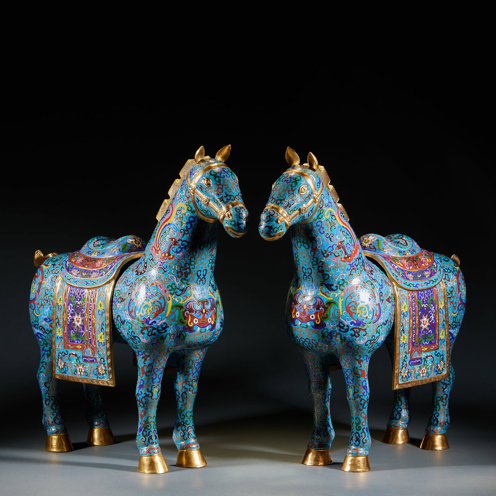 Qing Dynasty Enamel Colour Steed, A Pair: Qing Cloisonne Steed Pair: Crafted of copper-body gilt cloisonne, blue glaze ground decorated with interlocking flower and auspicious beast patterns via wire inlay and color filling. Horse head, saddl