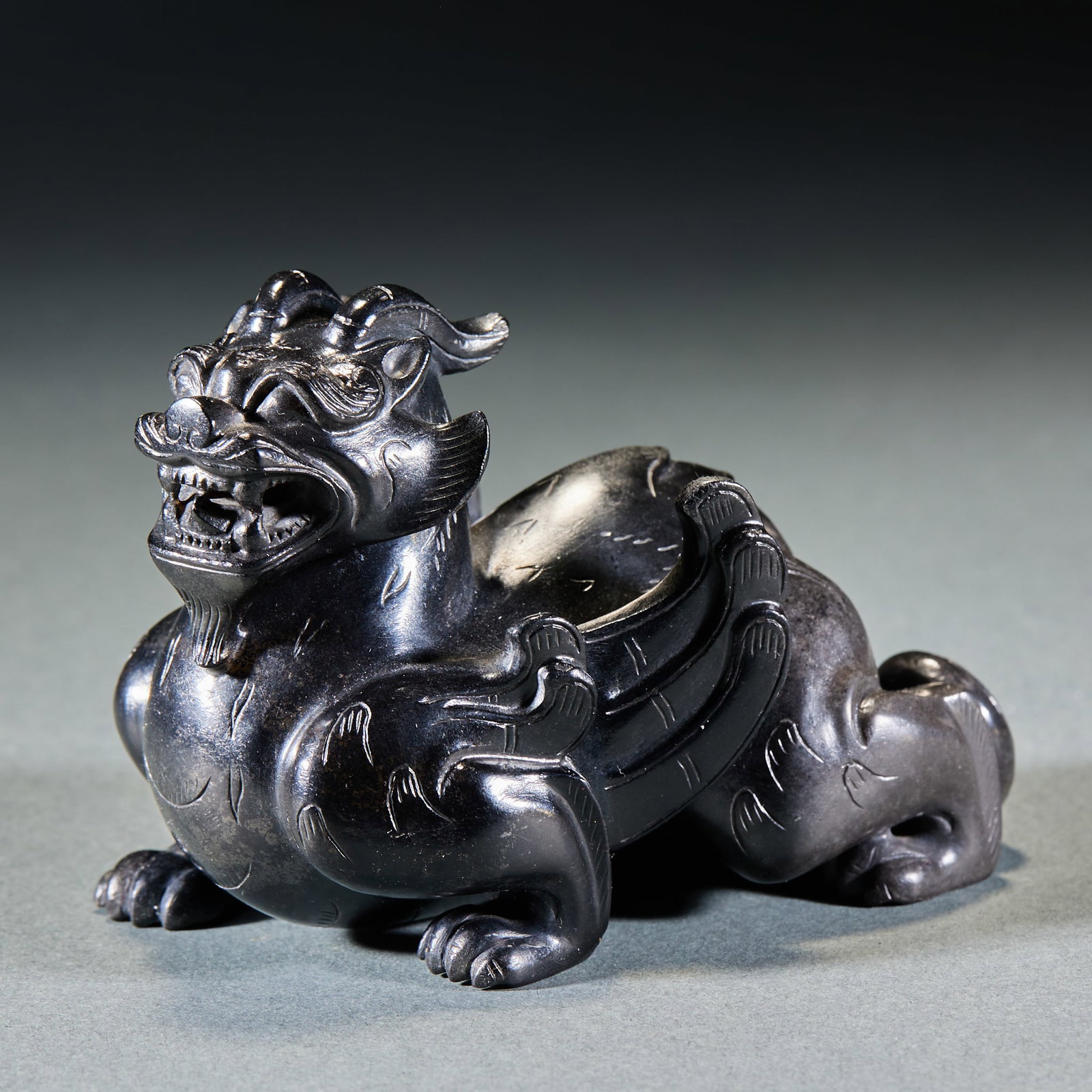 Han Dynasty Black Imbued Winged Auspicious Beast Jade Ornament: Han Dynasty Black Mottled Winged Mythical Beast Jade Ornament: Made of Hetian jade with black natural mottling, carved with winged mythical beast and dignified expression; Height 6.8cm, length 9.7cm, 