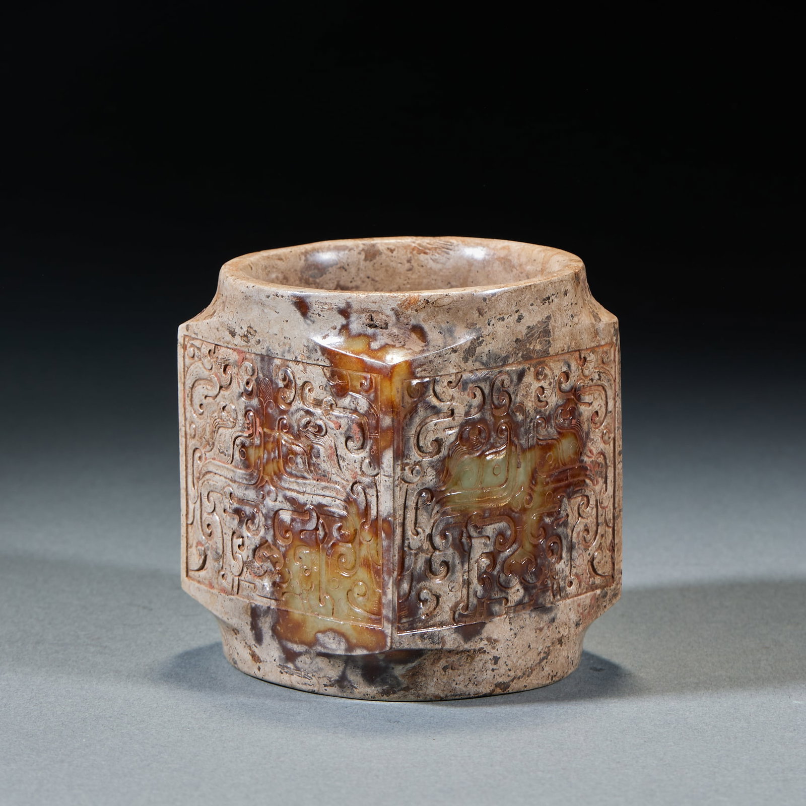 Beast Mask Jade Cong: Beast Face Jade Cong: Made of jade with natural mottling, Cong body relief carved with mysterious beast face patterns and primitive shape; Height 9cm, diameter 8cm; A ritual vessel of the Shang and Zh