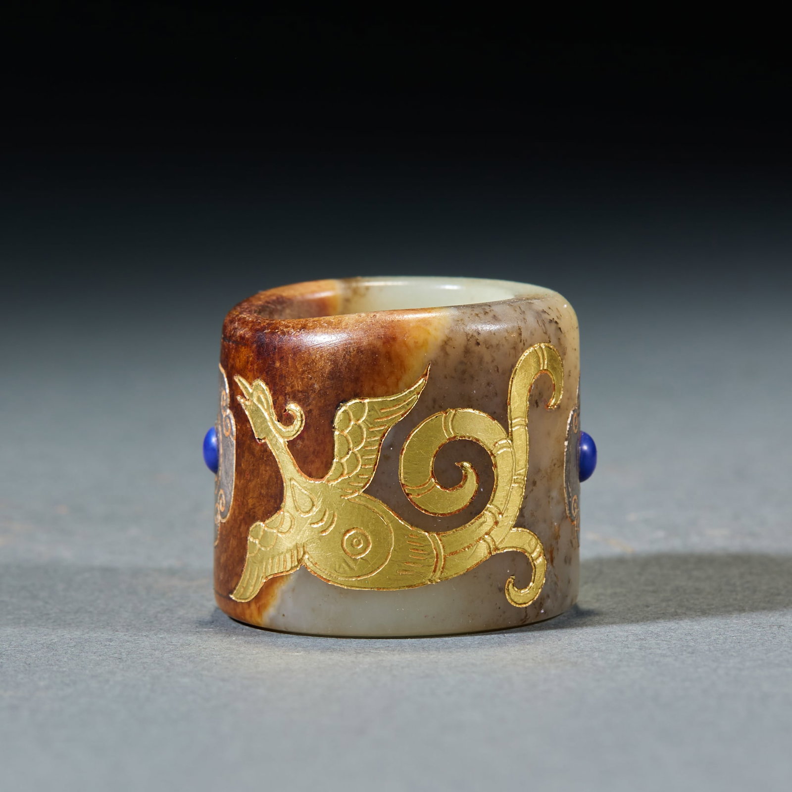 Gold Inlaid Jade Archer Ring: Gold-Inlaid Jade Thumb Ring: Made of jade with gold inlay and gemstone decorated phoenix patterns and regular shape; Height 3cm, inner diameter 2.1cm, weight 43g; A noble ancient ornament with delicat