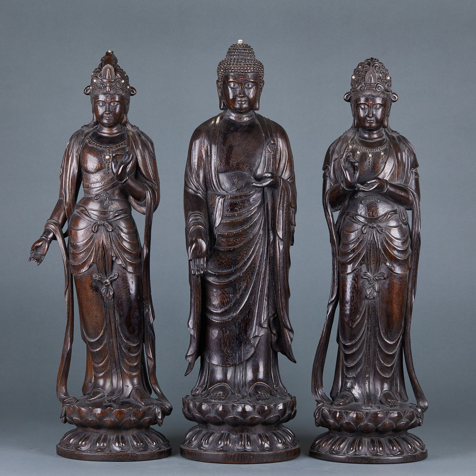 Agarwood Three Lives Buddha Statue: Agarwood Three Saints Standing Buddha Statue: Carved from agarwood into three standing Buddha statues with lotus base; Height 68cm, length 19cm, width 11cm; Solemn statue shape and fine carving make