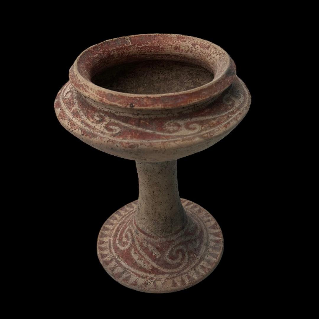 Ancient Bang Chiang footed vessel: Ancient Bang Chiang footed vessel from Thailand, ca. 300 BCE. Painted in red geometric patterns with cream ground. Four perforated holes for suspension. 10.5" H. Ex. Windsor, CT. collection, acquired 