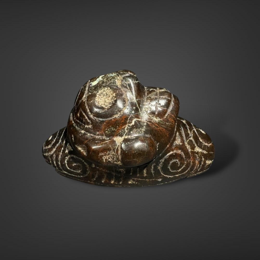 Miniature Pre-Columbian Taino stone zemi: Miniature Pre-Columbian Taíno stone zemi, originating from the Caribbean, dated between 1000-1500 CE. This carved object represents a Taíno deity or ancestral spirit, known as a zemi, depicted with 